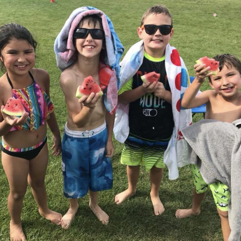 Children hold watermelon and smile for the camera at Alliance Recreation Center