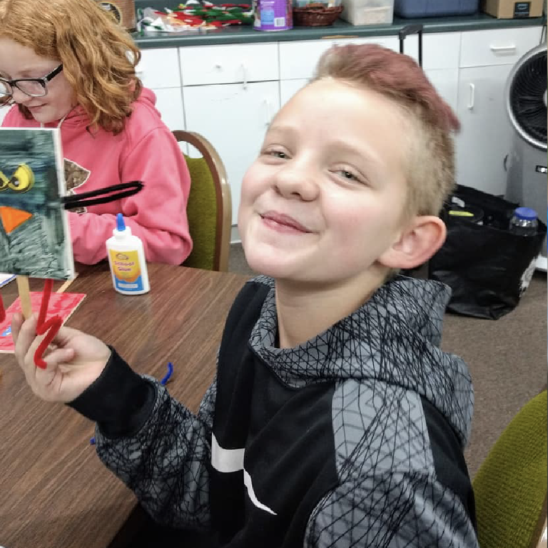 A boy smiles at the camera while participating in a program at the Carnegie Arts Center in Alliance, NE